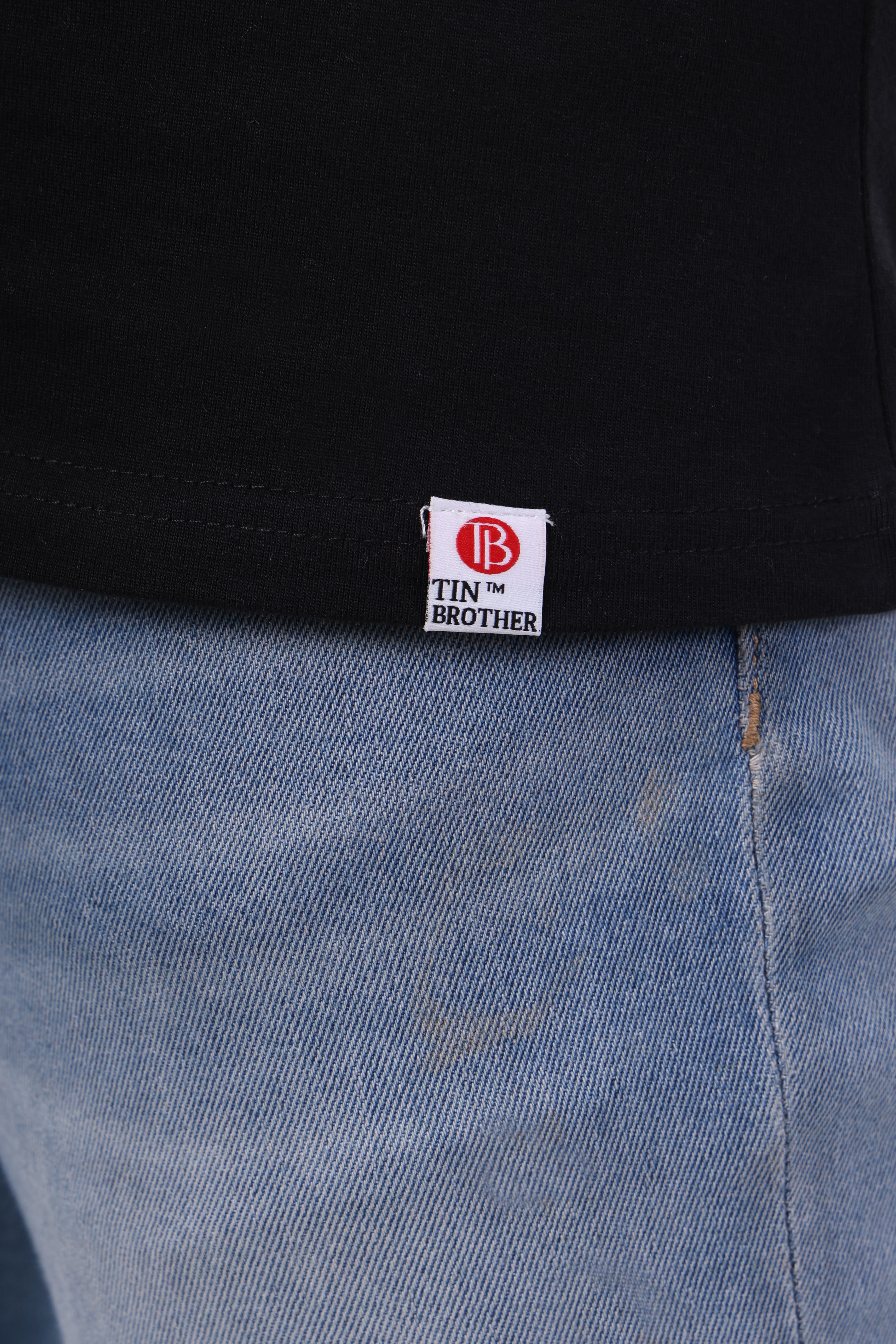 Brand tag close-up shot on Tin Brother t-shirt – stitched label on black fabric

